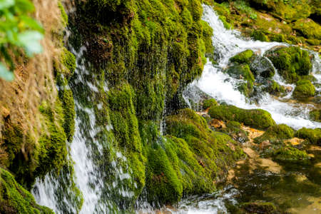 Ecology and nature. The source of clean drinking spring water among stone rocks and moist fresh green moss.の写真素材