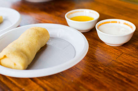Pancake on a plastic plate. Honey and sour cream in the background.の写真素材
