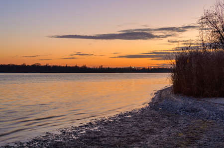 Scenic sky over the river at sunset time. View from the shore.
