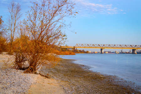 A long railway bridge over the river. View from the shore at sunsetの写真素材