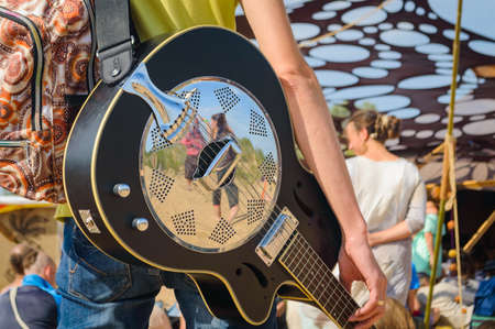 Guitar with a metal overlay on the shoulder of a man.