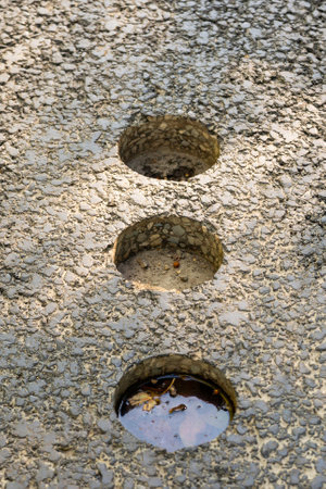 Holes in asphalt pavement, drilled cylindrical specimen for laboratory testing.の写真素材
