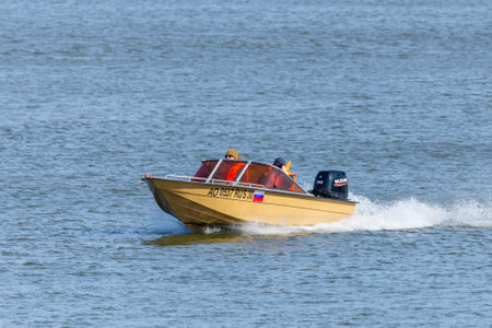 Astrakhan, Russia - October 06, 2019: Two man at motor boat racing through the river.のeditorial素材