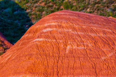Eroded red hill with white layers on a slope of hill.の写真素材