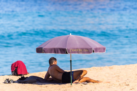 Portugal, Praia Santa Rita Norte, October 04, 2018: People relaxing on sand beach under sun umbrellas.のeditorial素材