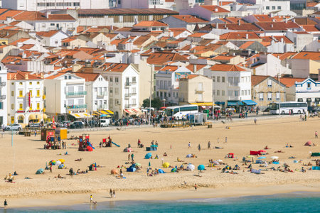 Nazare, Portugal - 05 October 2018: Beach of Nazare from sea side with tourists relaxing on the sand.のeditorial素材