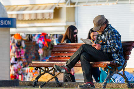 Russia, Gelendzhik, May 01, 2019: Retired man reading his newspaper on the bench.のeditorial素材