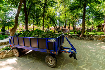 Blue modern trailer for a tractor with grass and ground in a botanical garden.の写真素材