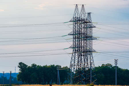High voltage lines and power pylons in a flat and green agricultural landscape.の写真素材