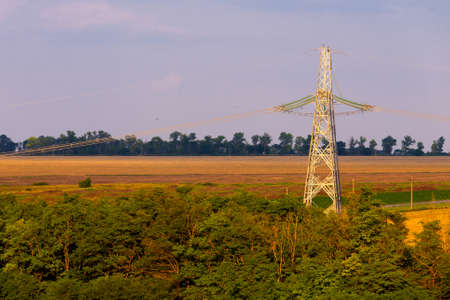 High voltage lines and power pylons in a flat and green agricultural landscape.の写真素材