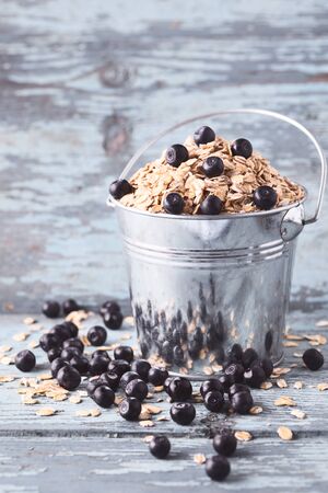 Oat flakes with blueberry in a bucket on wooden background& Space for text.の写真素材