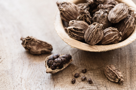 Black cardamom whole seed in a bowl on wooden background indian spice close-up with copyspaceの写真素材