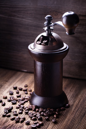 Whole coffee beans in coffee grinder on wooden background.の写真素材