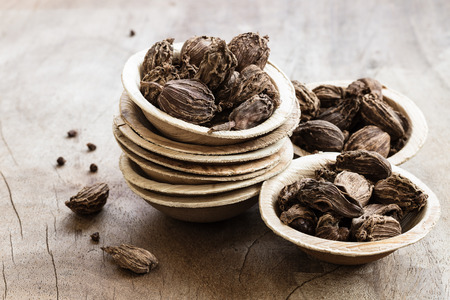 Black cardamom in bowls on wooden background indian spice close-upの写真素材