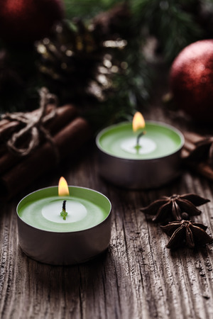 Christmas decorations: fur-tree branches, red balls, green candles, cone, cinnamon sticks and anise stars on a rough wooden background with a copy space. Toned image.の写真素材