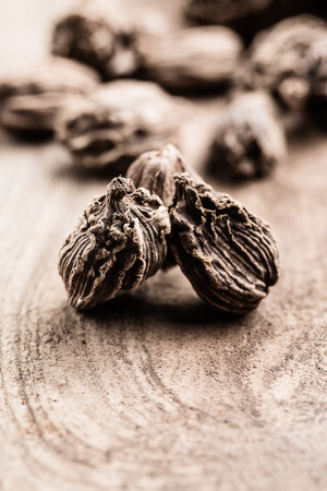 Whole black cardamom on wooden background with copy space vertical. Indian spices.の写真素材