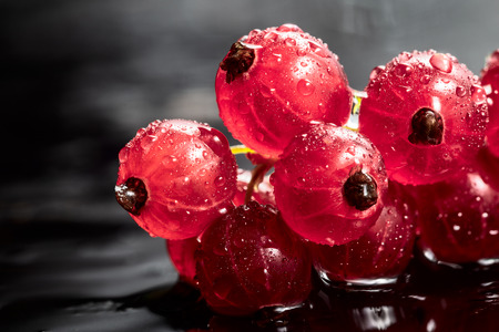 Red currant with drops of water on black background with copyspace close-up. Healthy foodの写真素材