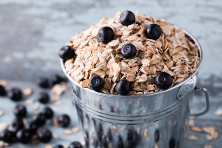 Oat flakes with blueberry in a bucket on wooden background. Close-up shot.の写真素材