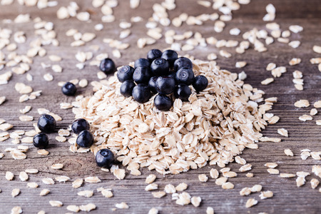 Raw oat with blueberry on top on wooden background.の写真素材