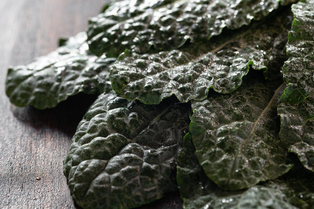 Fresh Kale leaves on brown wooden table close-up. Dark photo.の写真素材