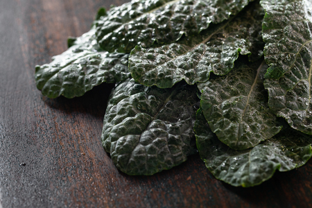 Fresh Kale leaves on brown wooden table with copyspace. Dark photo.の写真素材