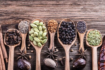 Different types of whole Indian spices in wooden background close-up.  Black pepper, fenugreek, anise, cinnamon, cardamom, nutmeg, clove, cumin. Healthy food.の写真素材
