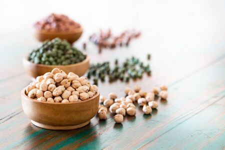 Colored chickpeas (red, green, white) in wooden bowls on rustic background. Vegetable proteins. Healthy eating concept. Indian food.の写真素材