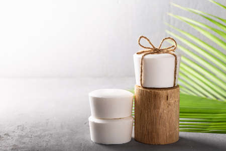 Handmade natural herbal coconut oil soap white color with palm leaf on gray concrete background....