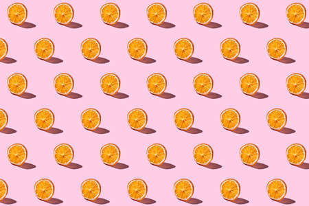 Trendy fruit pattern made with dried orange slices on bright light pink background. Creative food...