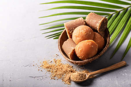Different shape of organic brown palm sugar or coconut sugar made from coconut juice on gray concrete background with copyspace.の写真素材