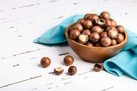 Organic ripe whole Macadamia nuts in bowl on old white wooden rustic table. Healthy vegan vegetarian food, vitamin.の写真素材