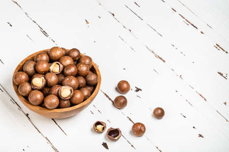 Organic ripe whole Macadamia nuts in bowl on old white wooden rustic table. Healthy vegan vegetarian food, vitamin.の写真素材