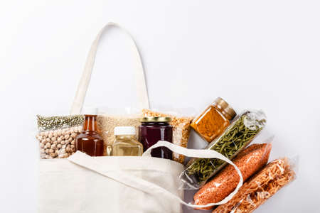 Healthy vegan food supplies on white background with copyspace. Group of colorful various cereals, seeds, nuts and legumes in plastic wrap. Food delivery, donation, coronavirus quarantine.の写真素材