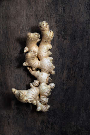 Fresh organic ginger root on dark old rustic background with copyspace top view vertical shot....