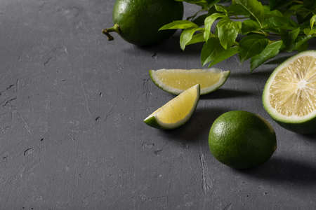 Juicy green limes on gray concrete background. Healthy eating, detox, diet.
