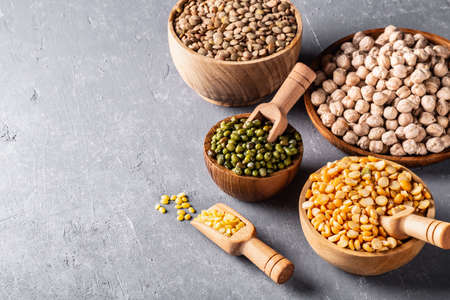 Assortment of beans, legumes on gray concrete background. Source of vegetable protein, eating...