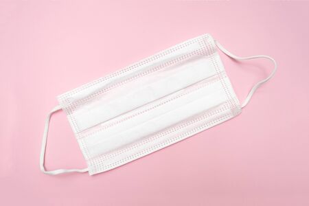 Medical surgical textyle filter protective mask on pink background, illness and flu defense.
