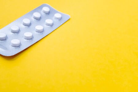 A blister pack of statins, pills tablets for lowering cholesterol on yellow background, prevention...