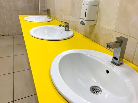 Row of yellow modern washing basin in a public restroom.の写真素材