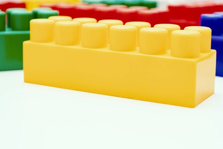 Many colorful toy plastic bricks, kit of blocks for building and constructing with a yellow one close up on white background with copy space.の写真素材