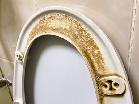 Dirty unhygienic seat of a toilet bowl with limescale stain at public restroom close up.の写真素材
