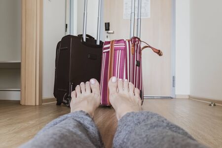 A couple of different suitcases, luggage in a hotel room standing near the door and woman legs...