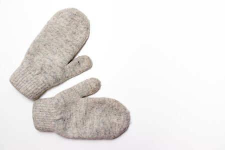 Gray soft knitted mittens on white background with copy space, flat lay.