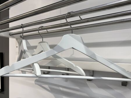 Group of white wooden empty handgers in a wardrobe, hanging on a wooden tube.の写真素材