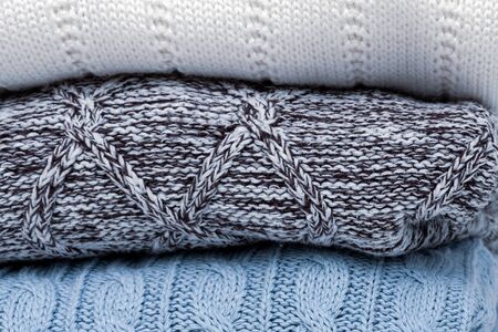 Stack of cozy comfortable homely clean washed knitted pullovers as a background.