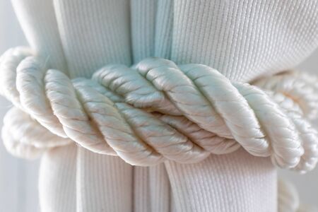 Knob of the white rope on a fabric curtain close up.の写真素材