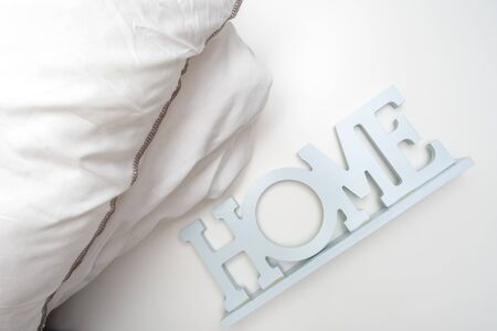 Home order background, interior details, a stack of cozy soft white bedding, pillows and blanket with a sign home, bedroom textile concept.の写真素材