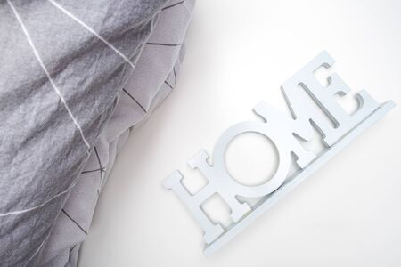 A stack of cozy soft bedding in shades of gray, pillows and blanket with a sign home, home textile concept.の写真素材
