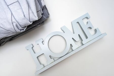 A stack of cozy home textile in shades of gray bed linen, bedding with the sign home near it.の写真素材