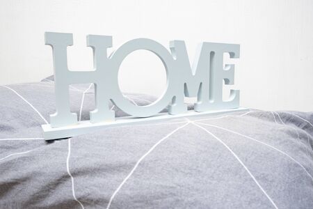 A stack of cozy soft bedding in shades of gray, pillows and blanket with a sign home, home textile concept.の写真素材